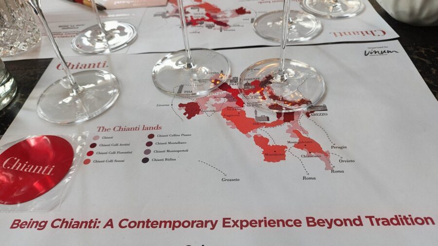 Bei einer Chianti DOCG-Masterclass liegen Gläser über einer Karte der Chianti-Landschaften, mit VINUM-Branding und dem Motto "Being Chianti".